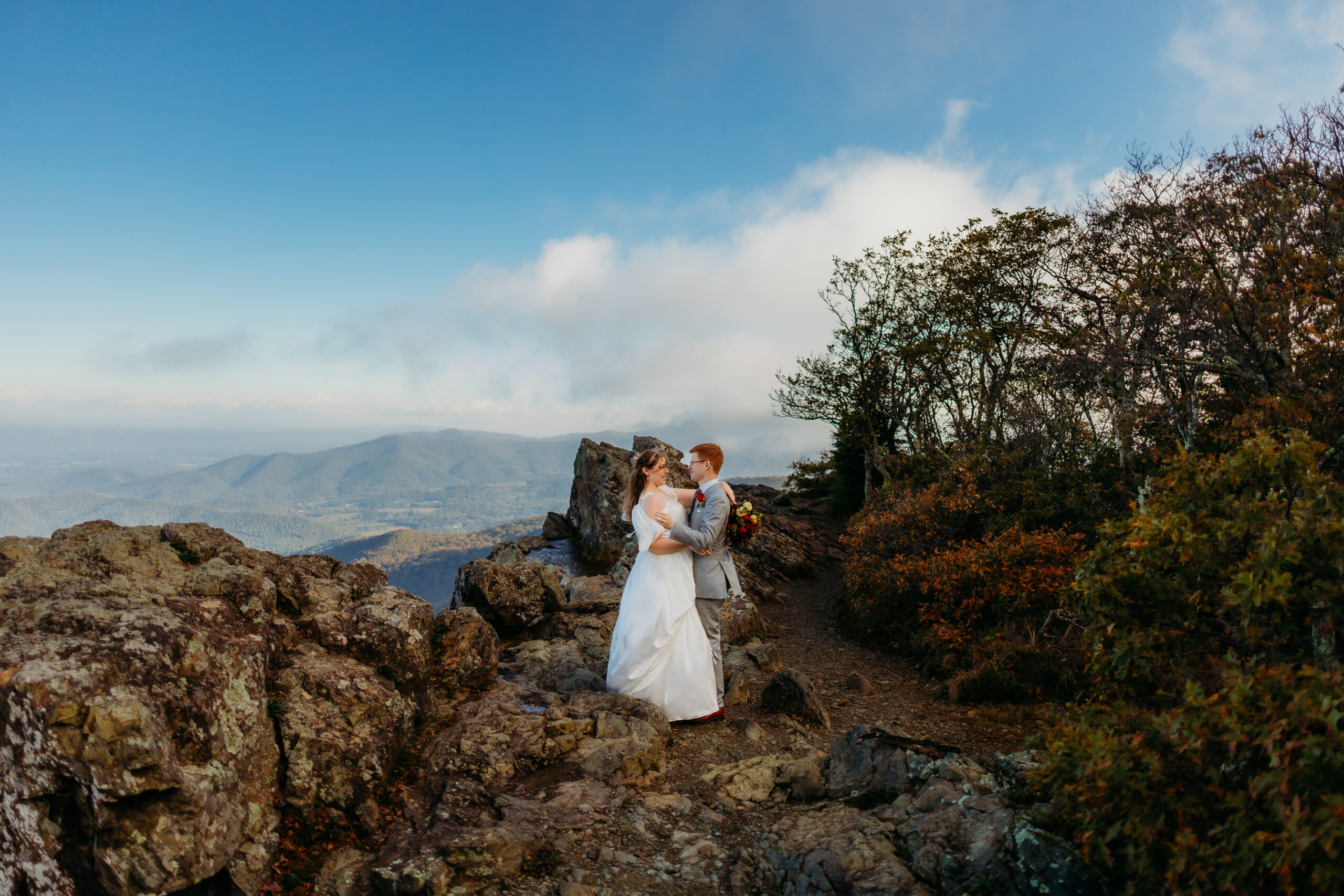 A couple exchanging vows at a scenic overlook in Shenandoah National Park, surrounded by vibrant autumn foliage and rolling mountains in the distance.